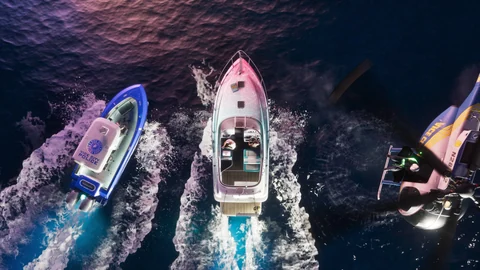 Vue d’en haut, de nuit : une vedette marquée Vice City Police, un bateau de plaisance et un hélicoptère aux couleurs de Vice City, capture officielle de GTA VI